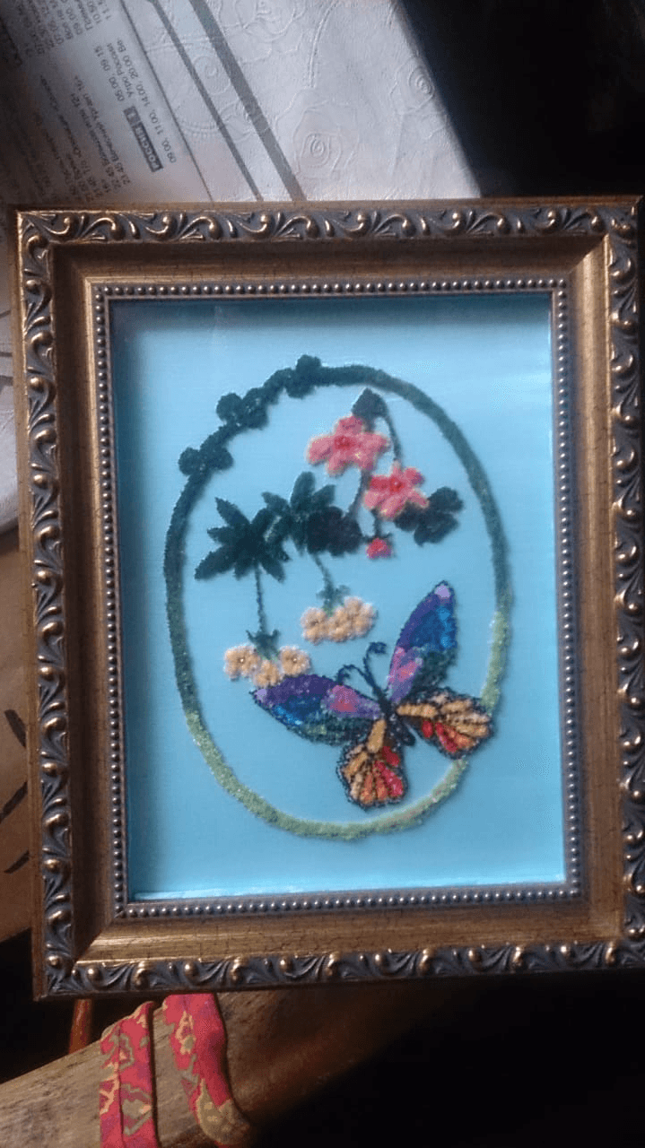 Ornately framed wall art of raised nap fabric flowers and butterfly